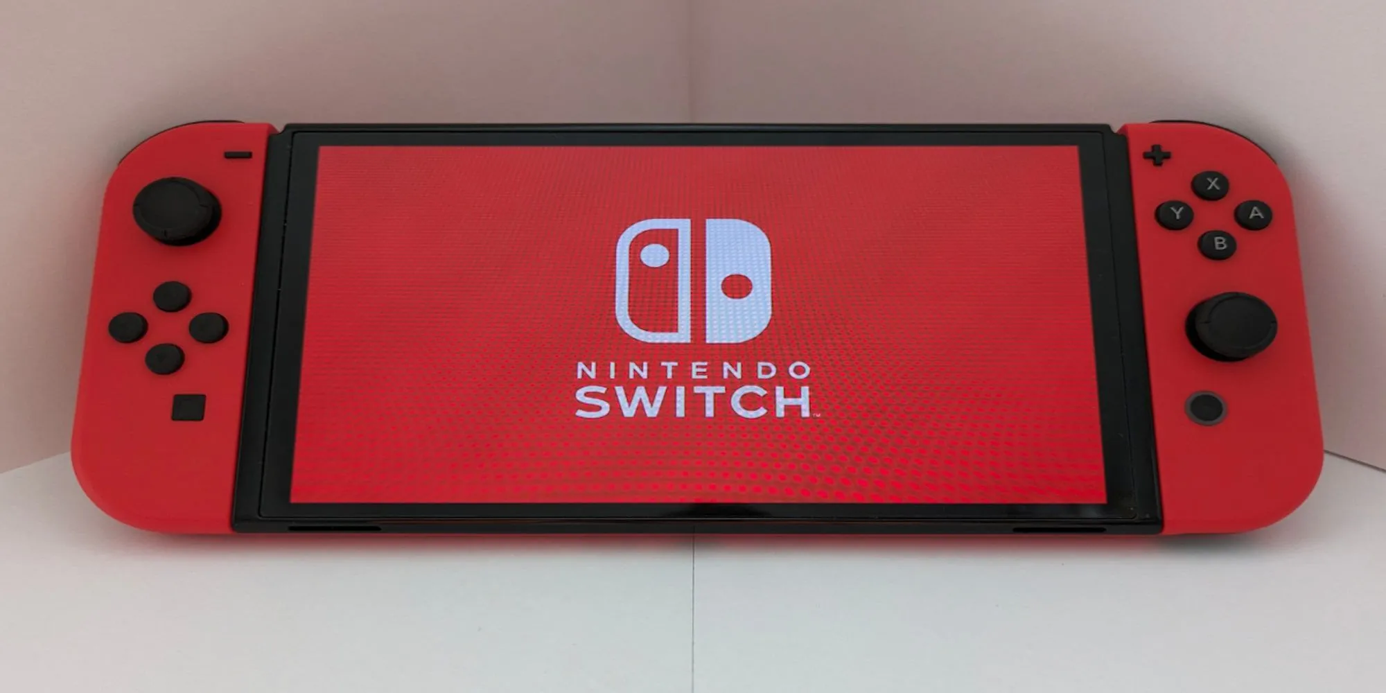 Máy chơi game Nintendo Switch màu đỏ đặt trên nền trắng, minh họa cho việc thiết bị vẫn đang được hỗ trợ